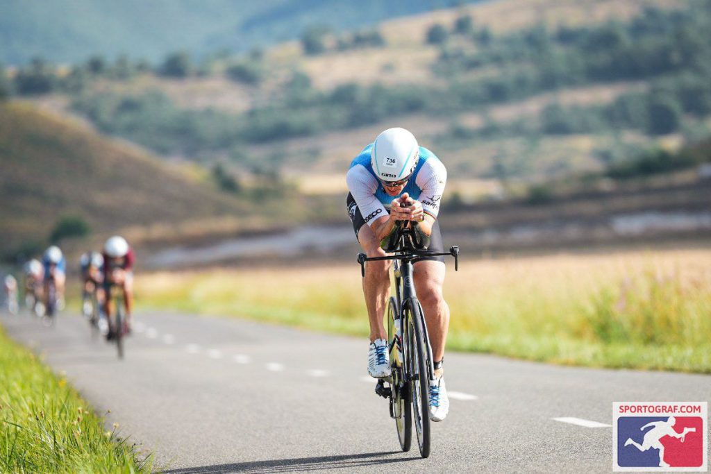 Entrenador de triatlón en posición aerodinámica durante el sector de ciclismo en un paisaje de montaña